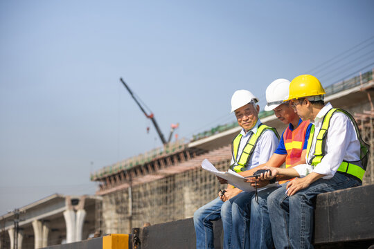 Group of civil engineers and architects reviewing construction plan at building site, Team of construction supervisors examining architectural drawing on outdoor site