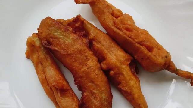 Closeup top view of traditional south indian kerala spicy tea snack mulaku bajji served on plate with white table background.