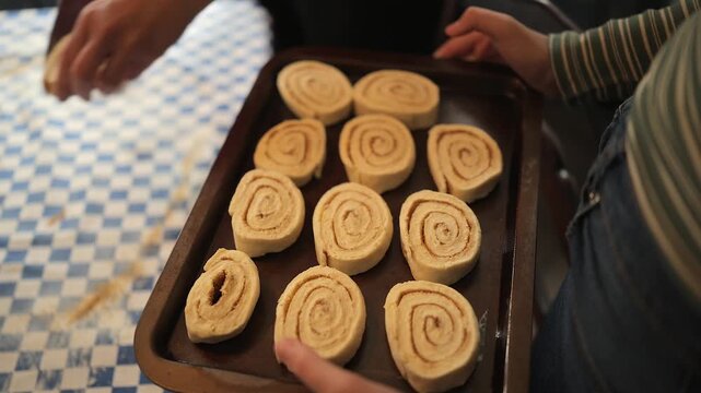 High angle: Cinnamon buns are placed onto pan prior to baking in oven