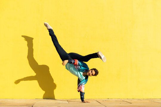 Acrobat doing movement training in front of a yellow wall