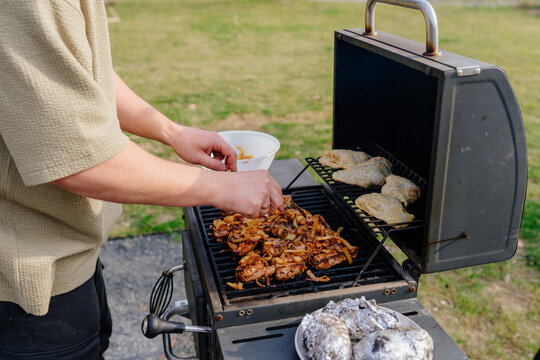Close up of Man Hands Grilling Meat And Vegetables On Outdoor Barbecue