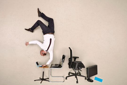 Businessman doing handstand while working on laptop