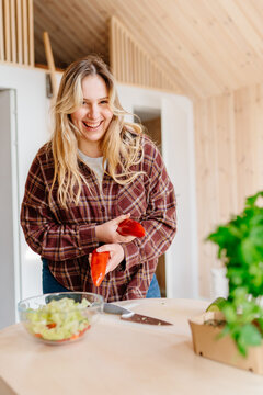 Laughing Young Woman Preparing Fresh Salad In Cozy Cabin Kitchen