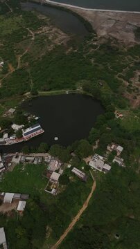 Top-down aerial view of the sacred Gopi Talav lake surrounded by lush green forest near Dwarka, Gujarat.