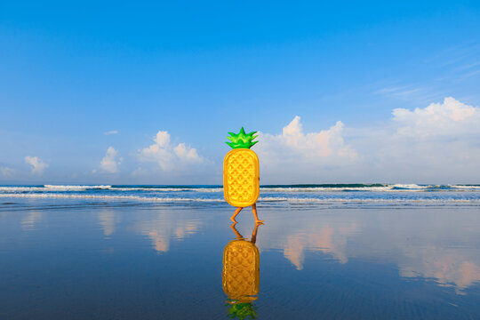 Woman with pineapple float walking at beach