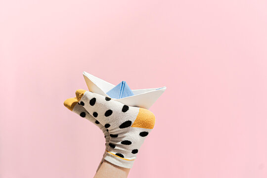 Paper boat on the feet of a girl wearing dotted socks