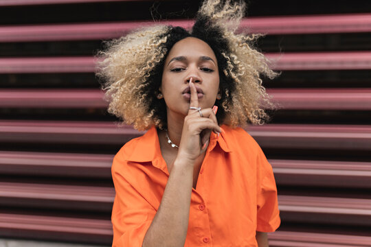 Woman making silence gesture in front of wall