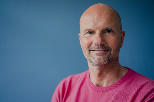 Portrait of smiling mature man wearing pink pullover