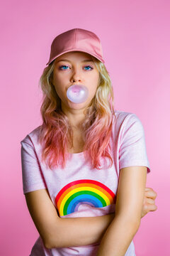 Portrait of cool young woman with bubble gum in front of pink background
