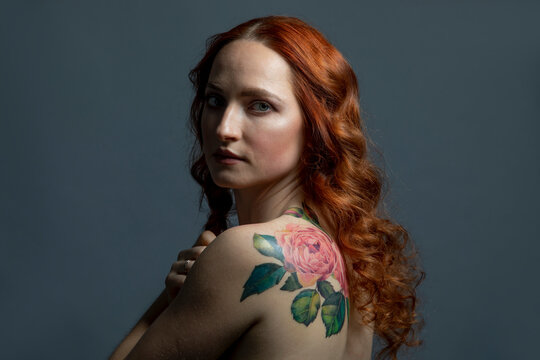 Beautiful woman with flower tattoo against gray background