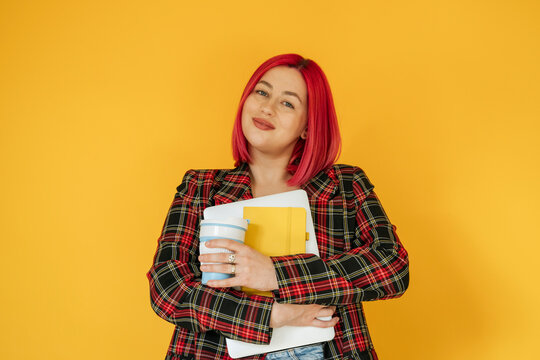 Smiling woman holding laptop against yellow background