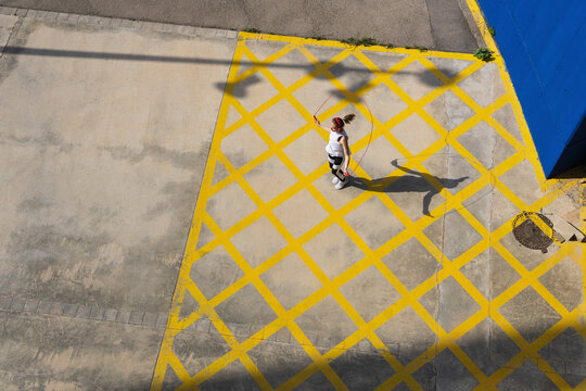 Female athlete jumping rope on road during sunny day