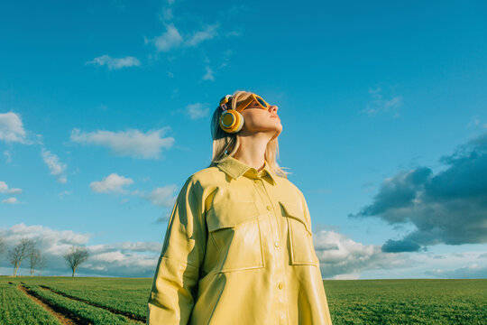 Woman wearing yellow shirt standing under blue sky