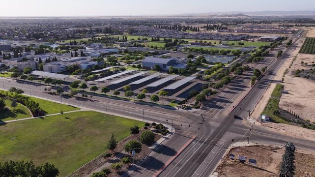 Stunning aerial perspective revealing the sprawling campus of Clovis Community College, featuring academic buildings, solar panel carports, lush green fields, and surrounding neighborhoods