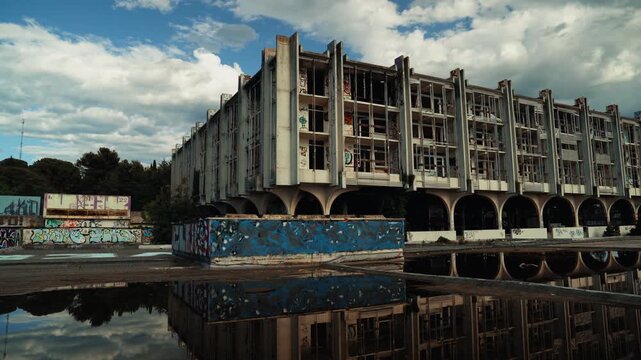 Wide view of the abandoned Haludovo hotel complex in Malinska on Krk Island, Croatia, with graffiti, reflections and dramatic cloudy sky. Former Yugoslav tourist resort in decay.