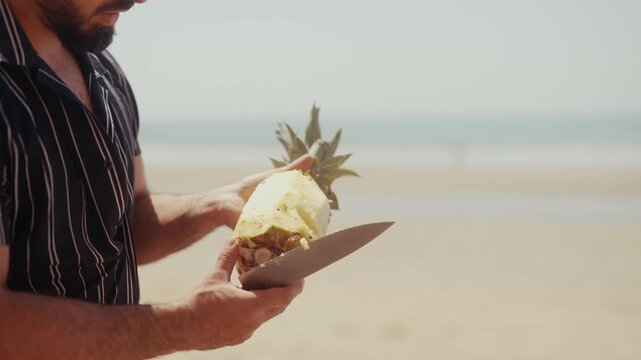 Person peeling a pineapple on a sunny beach