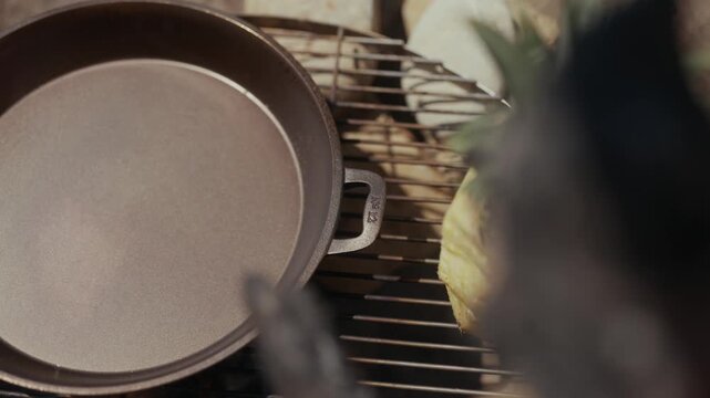 Cast iron pan on a grill with corn and blurred foreground