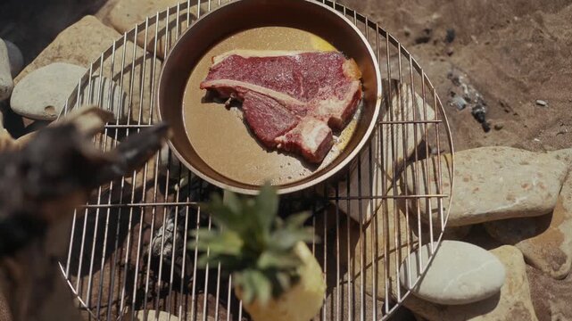 T-bone steak cooking in cast iron pan on outdoor grill