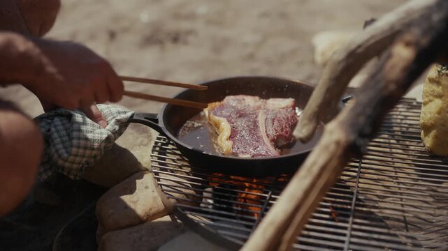 Cooking a T-bone steak in a cast iron pan outdoors