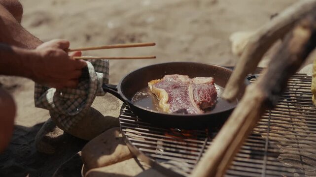 Cooking steak in a cast iron pan over an open fire