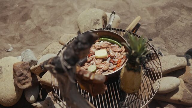 Cooking shrimp and pineapple on a grill over an open fire
