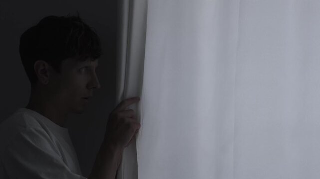 Paranoia and anxiety concept with suspicious person carefully looking through curtain, psychological fear, stress and unsafe feeling atmosphere, close-up
