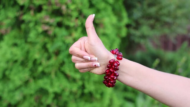 A fashionable accessory: a red garnet bracelet on a beautiful female hand with a French manicure.