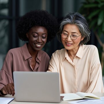 Two women sharing a laptop and smiling during a mentoring session for education, teamwork or consulting background and banner design