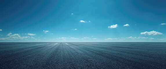 Fototapeta premium Expansive asphalt surface under a clear vibrant sky with few clouds