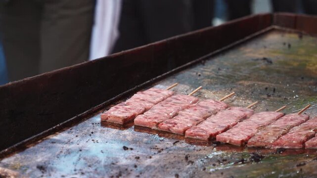 Meat Skewers Grilling on Hot Flat Iron Griddle at Street Food Market