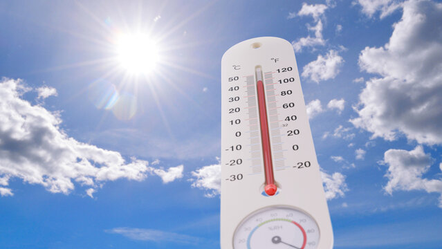 Outdoor thermometer showing extreme high temperature under a bright scorching sun and blue sky with clouds, symbolizing a severe summer heatwave, global warming crisis, and climate change.