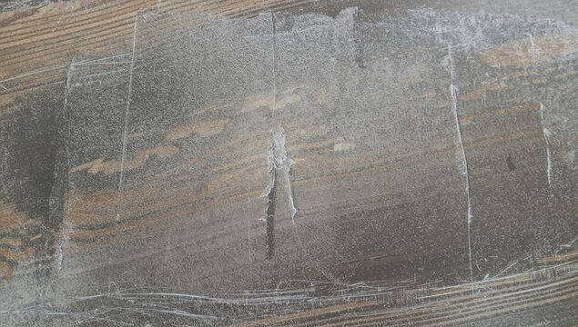 Close view of chalk dust accumulation on textured wood blackboard