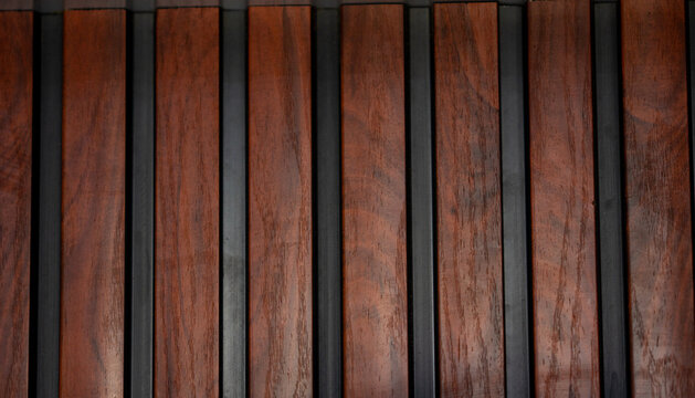 Dark brown wooden wall panel with vertical timber strip and thin black divider detail