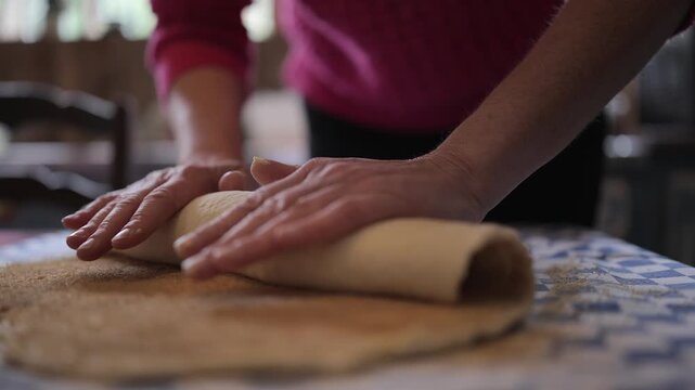 Cinnamon bun dough is rolled up on kitchen table, close-up baking prep