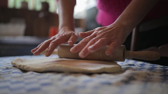 Woman uses rolling pin, flatten dough on home table for cinnamon buns