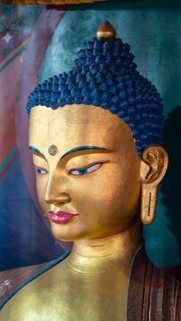 Golden Buddha statue face with blue hair and third eye in temple