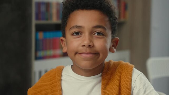 Close up cute African American ethnic little child son study writing school test happy write schoolwork at library motivated kid boy pupil schoolkid schoolchild studying positive looking at camera