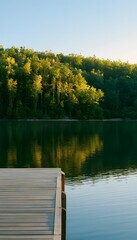 Obraz premium Tranquil lakeside pier reflects golden sunlight peaceful forest serene landscape photography evokes calm beauty