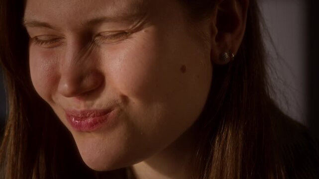 Close up shot of Caucasian young woman biting into sour lime citrus and scrunching face over raw taste sensation, candid scene lit by golden sunlight, copy space