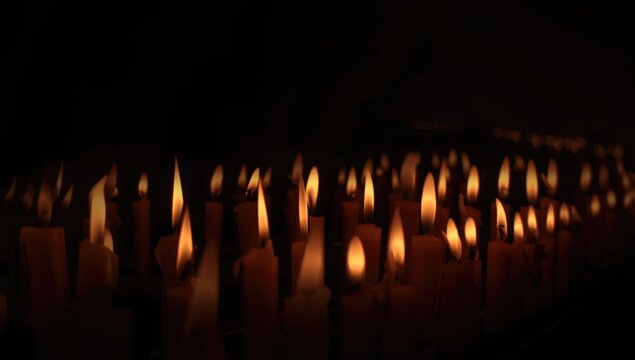 Flaming candles shining quietly in darkness with a memorial backdrop
