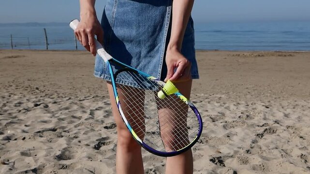 Close-up of woman with Badminton racket on sunny beach during summer.
