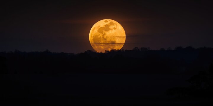 Giant supermoon rising over a serene dark sky landscape