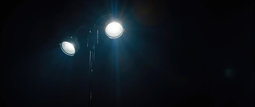 Dual spotlight street lamp illuminating an urban night scene with intense light contrasts