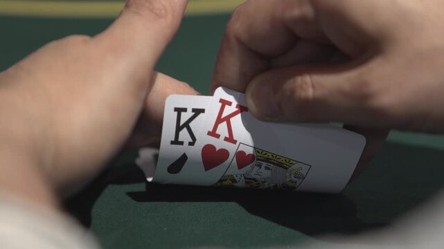 Close-up shot of a poker player checking cards during a Texas Hold&rsquo;em game. Gambling, betting, casino and poker concept footage.
