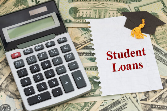 Student loans text on a torn paper and grad cap on twenty dollar bills for cost of education