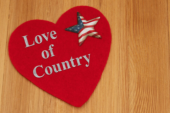 Love of Country text on a red heart with American flag star on a wood desk for military appreciation