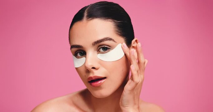 Eye patches, face and skincare with woman in studio for aesthetic, glow or skin hydration. Cosmetics, girl and gel pad for dermatology with self care, beauty or collagen treatment on pink background