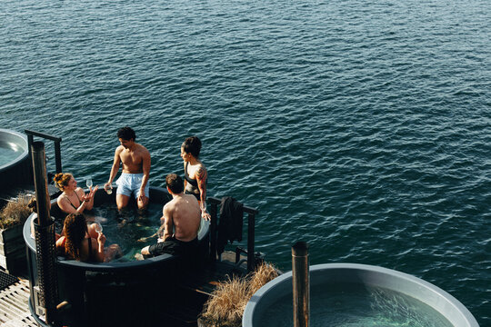 An outdoor spa brings people together by the water for a relaxing escape with drinks