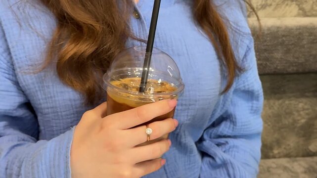 Preparing iced latte in plastic cup with milk coffee and ice cubes