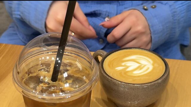 Young woman picking cuticles near nails while choosing between iced and hot latte